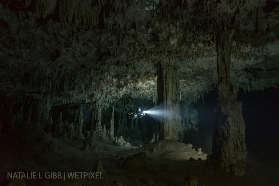 Diver Stephanie Lee hovers between two massive columns at Cenote Nai Tucha. Video lights were placed behind each column, with weaker lights behind the photographer. 