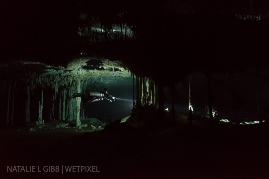 Diver Alex K.S. Fraser floats in front of a single video light at Nohoch Nah Chich. Bubbles on the cave ceiling create a mirror effect.