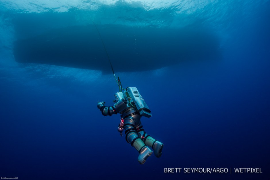 The Exosuit, a single person one atmosphere diving hard suit is suspended from the Hellenic Navy vessel HN THETIS.